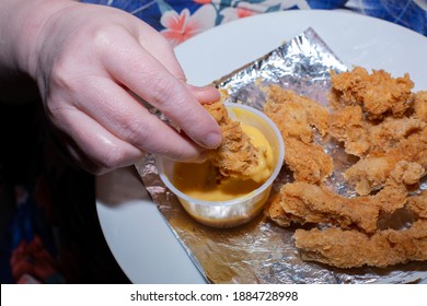 Woman Dipping A Chicken Tender In Honey Mustard Sauce