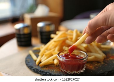 Woman dipping French fries into red sauce in cafe, closeup - Powered by Shutterstock