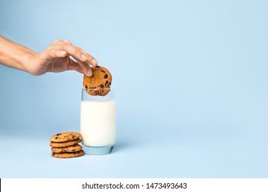 Woman dipping tasty cookie in glass of milk on color background