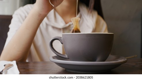 Woman Dipping Tea Bag In Cup At Restaurant