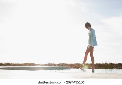 Woman Dipping Toe In Swimming Pool