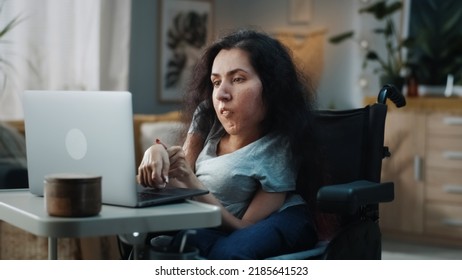 Woman with disability in a wheelchair at home browsing the internet, online shopping or use social media using a laptop at daytime in cozy room - Powered by Shutterstock