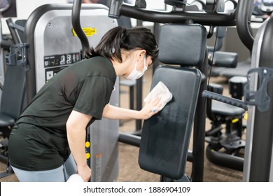 A Woman Disinfecting A Training Gym Machine.