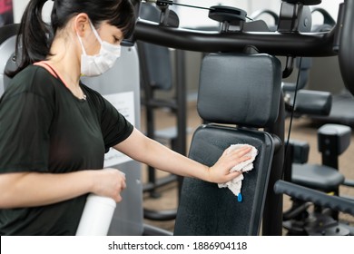 A Woman Disinfecting A Training Gym Machine.