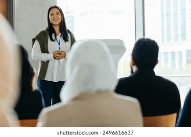 A woman displaying leadership while giving a talk at a business conference event. Engaging audience during a professional presentation. - Powered by Shutterstock