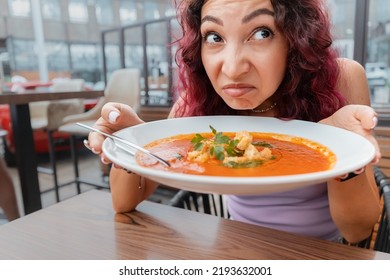 A woman dissatisfied customer of the restaurant sniffs the disgusting smell of a bowl of soup with spoiled ingredients and is going to complain to the chef