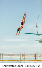 Woman diving into the pool from spring board. Female diver diving upside down into the swimming pool.