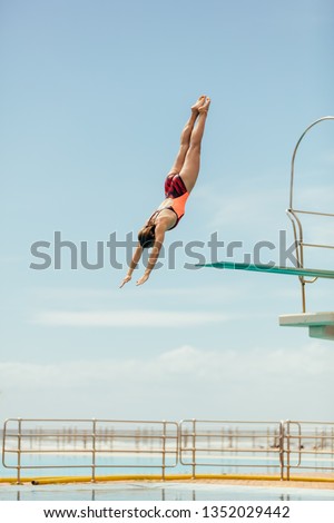 Woman diving into the pool from spring board. Female diver diving upside down into the swimming pool.