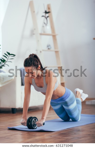 woman with do abdominal exercises with wheel.\
Workout exercise at home to lose\
weight