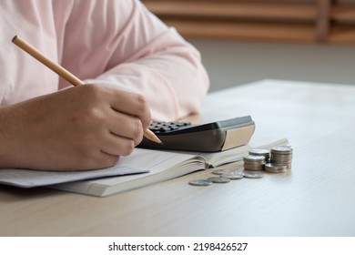 Woman Do Home Accounting And Calculating Book Bank Statement For Household Expense And Money Coins On The Table. Home Accounting Plan For Monthly Payment. Saving And Accounting Concept At Home.