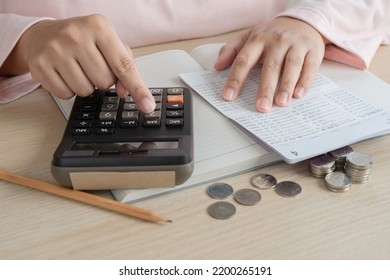 Woman Do Home Accounting And Calculating Book Bank Statement For Household Expense And Money Coins On The Table. Home Accounting Plan For Monthly Payment. Saving And Accounting Concept At Home.