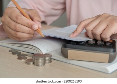 Woman Do Home Accounting And Calculating Book Bank Statement For Household Expense And Money Coins On The Table. Home Accounting Plan For Monthly Payment. Saving And Accounting Concept At Home.