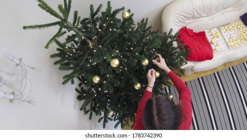 Woman Is Docorating Fir On Christmas Tree. She Is Hanging Golden Baubles, Christmas Ornaments. It's Christmas Time. The Time Lapse Movie.