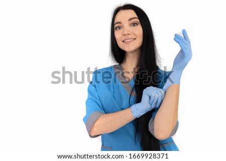 Woman doctor in blue uniform puts on gloves