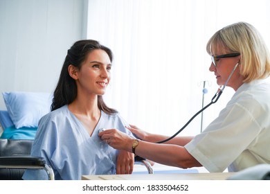 Woman Doctor Check The Pressure Of Women Patient's.The Female Doctor Smiled And Made Eye Contact With The Patient. Doctor Using Sphygmomanometer With Stethoscope Checking Blood Pressure To A Patient