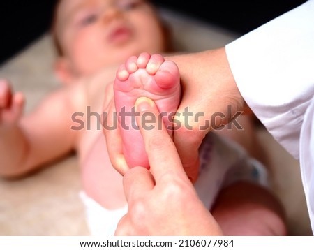 woman doctor checks the reflexes of a newborn baby on the sole of the foot. The baby squeezes his toes when checking the reflex