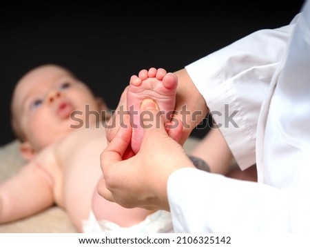 woman doctor checks the reflexes of a newborn baby on the sole of the foot. The baby squeezes his toes when checking the reflex