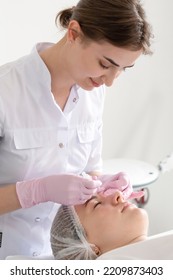 Woman Doctor Cosmetologist Dermatologist Makes Injections Of Botulinum Toxin For A Patient. Real Procedure Botox Injections In The Forehead And Around The Eyes