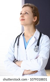 Woman Doctor With Crossed Arms Looking Up While Working In Hospital