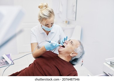 
Woman Doctor Dentist Works With An Elderly Man In A Dental Chair Treats Teeth And Shows X-rays