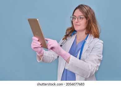 Woman Doctor With A Digital Tablet Apple IPad In A White Uniform On A Blue Studio Background - Moscow, Russia, August 12, 2021