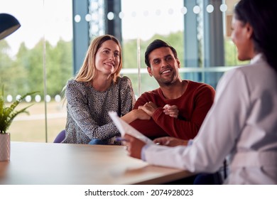 Woman Doctor Discussing Test Results With Smiling Couple n Hospital
