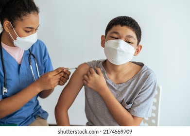 Woman Doctor Giving First Dose Of Covid Vaccine To Little Boy In Clinic Office.Vaccinating Children Against Coronavirus Concept.