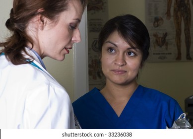 A Woman Doctor Giving Instructions To Her Nurse Upon Reviewing Lab Results.