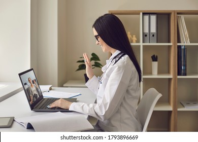 Woman Doctor In Her Office With Laptop Waving To Her Patient. Online Doctor Gives Remote Consultation Using Video Call To Patient Senior Woman.