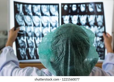 Woman Doctor Holding And Looking Out Of Focus Patient Bone X-ray Film Before Surgery.Image MRI And CT Scan At Radiology Orthopedic Unit In Hospital.Knee Join Xray For Treatment.Selective Focus.