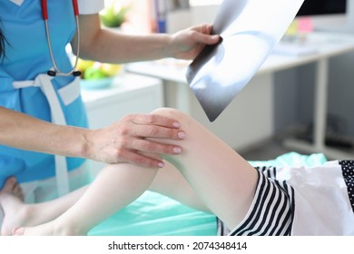 Woman doctor holding x-ray and examines child's leg - Powered by Shutterstock