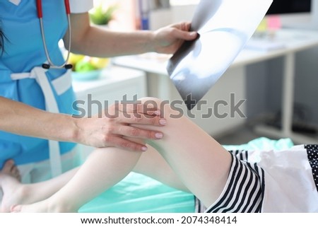 Woman doctor holding x-ray and examines child's leg
