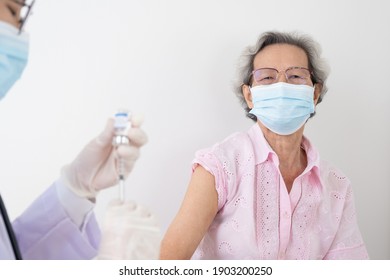 Woman Doctor Is Preparing A Vaccine For An Older, Gray-haired Asian Woman Wearing White Shirts To Build The Coronavirus Or COVID-19 Immune System.