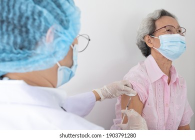 Woman Doctor Is Preparing A Vaccine For An Older, Gray-haired Asian Woman Wearing White Shirts To Build The Coronavirus Or COVID-19 Immune System.