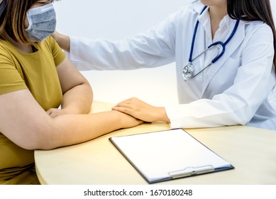 Woman doctor put her hand on the shoulder and hand of a fat woman and wearing mask to prevent germs, to comfort and encourage the patient , to people and health care concept.