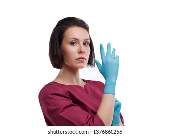 Woman Doctor Puts A Medical Glove On Hand. Close-up Portrait On A White Background. Serious Focused Doctor. European