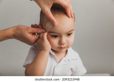 A woman doctor puts a plaster on the boy's forehead indoors. studio photo. health concept - Powered by Shutterstock