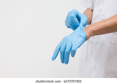 Woman doctor putting blue latex medical gloves on white background.Surgeon wearing gloves before surgery at operating room.Risk and infection control concept. - Shutterstock ID 1673707303