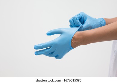 Woman doctor putting blue latex medical gloves on white background.Surgeon wearing gloves before surgery at operating room.Risk and infection control concept. - Powered by Shutterstock