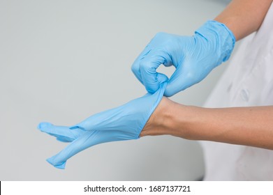 Woman Doctor Putting Blue Latex Medical Gloves On White Background.Surgeon Wearing Gloves Before Surgery At Operating Room.Risk And Infection Control Concept.