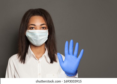 Woman doctor or scientist in a medical face mask showing stop pandemic gesture. Black woman in safety mask and medical gloves - Powered by Shutterstock