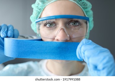 Woman doctor sealing her mouth with blue tape. Medical secrecy concept - Shutterstock ID 1917991088