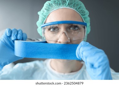 Woman doctor sealing her mouth with blue tape. Medical secrecy concept