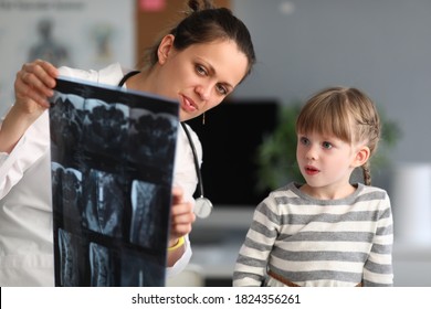 Woman doctor shows child patient an xray in clinic. Use of radiation diagnostics of diseases of skeletal system in pediatric practice concept.