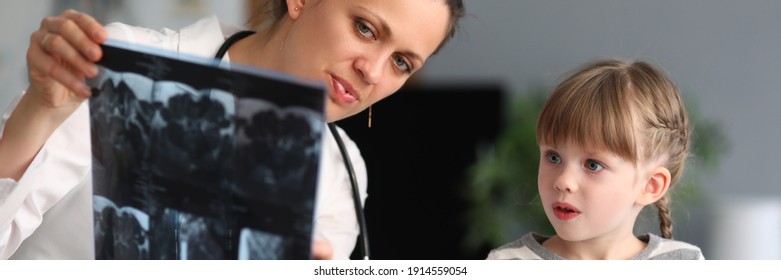 Woman Doctor Shows Child Patient An Xray In Clinic. Use Of Radiation Diagnostics Of Diseases Of Skeletal System In Pediatric Practice Concept.