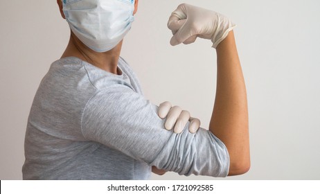 Woman Doctor With A Surgical Mask And White Rubber Gloves In Position Of  Rosie The Riveter 