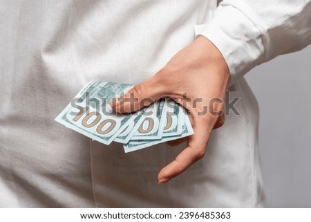 A woman doctor takes out a pack of one hundred dollar bills and a doctor's coat from her pocket.  Concept: corruption and bribery in medicine and healthcare.