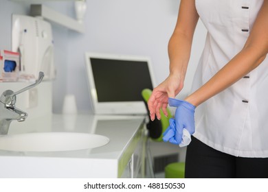 Woman Doctor Taking Off Medical Gloves After Working Day At Her Dentist Office.