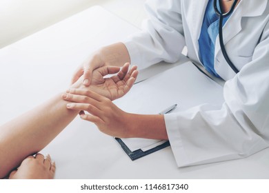 Woman doctor talks to female patient in hospital office while examining the patients pulse by hands. Healthcare and medical service. - Powered by Shutterstock