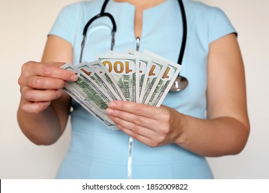 Woman Doctor With US Dollars In Hands. Concept Of Medical Staff Salary, Money For Medical Exam Or Expensive Health Care